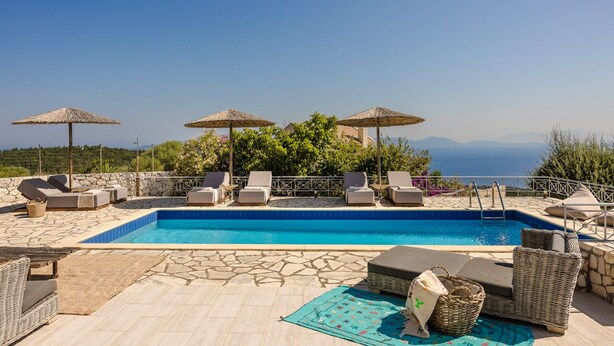 A pool area with lounge chairs, umbrellas, and a view of the sea. - Villa Renata. (Katsarata)