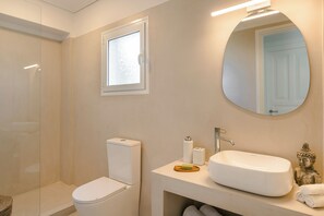 A bathroom with a toilet, a sink, a mirror, and a window. - Villa Renata. (Katsarata)