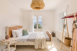 A bedroom with a bed, a bedside table, a hanging basket, and a view of the outdoors. - Villa Renata. (Katsarata)