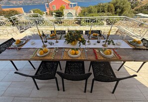 A table set for a meal with a view of the sea and a red building in the background. - Villa Renata. (Katsarata)