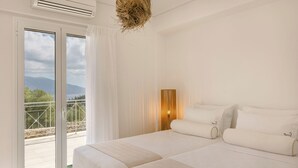 A bedroom with a large bed, a nightstand, a lamp, and a view of the outdoors through a sliding door. - Villa Renata. (Katsarata)