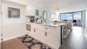 A modern kitchen with white cabinetry, a large island, and a chandelier. - Oceanfront Lux at Palms Resort Views and Amenities (Myrtle Beach)