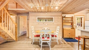 Un interior de madera con una mesa de comedor y sillas, una zona de cocina y una escalera.