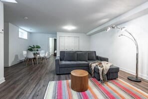 A modern living room with a grey sofa, a round wooden coffee table, and a colorful striped rug.