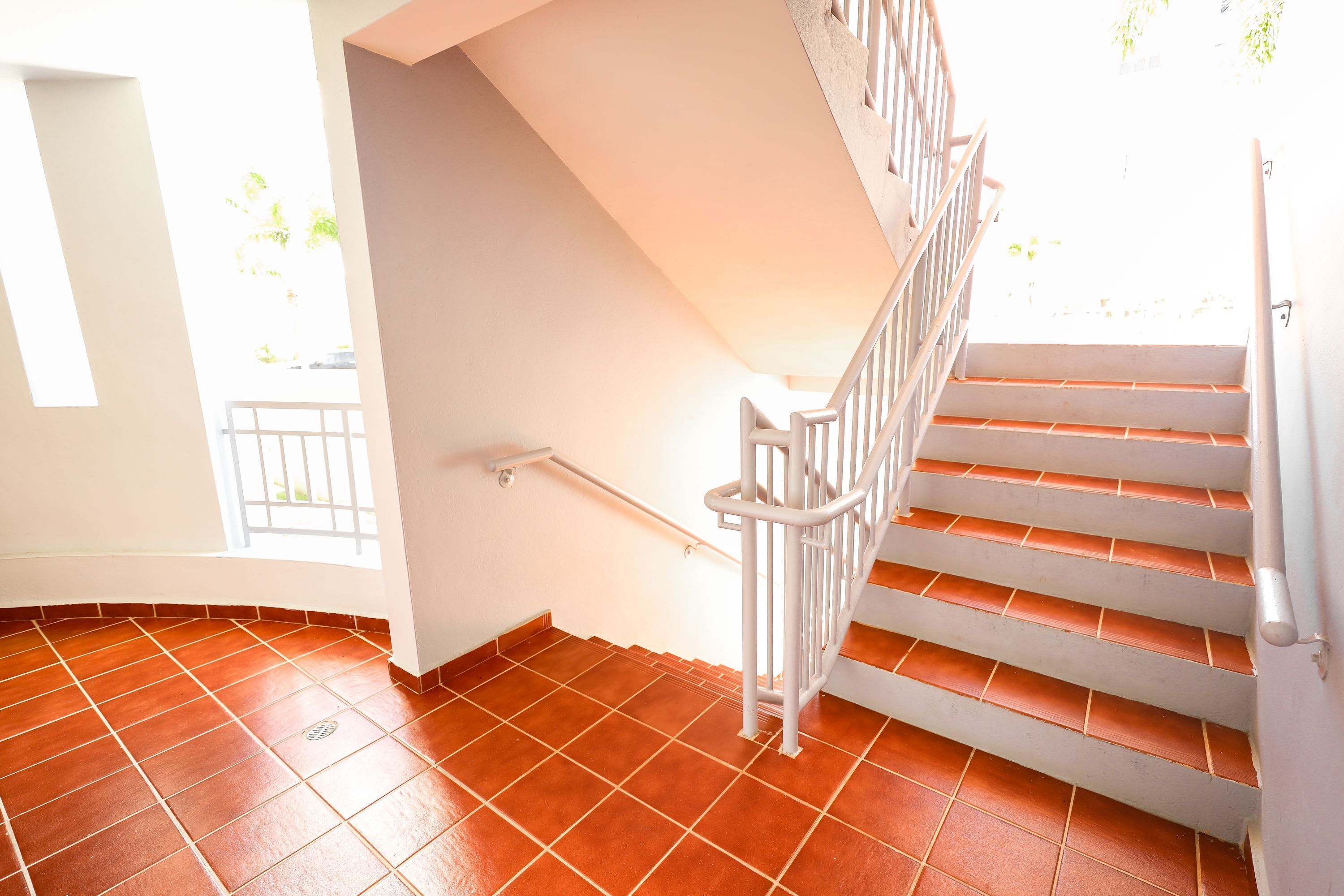 A staircase with white railings and terracotta tiles.