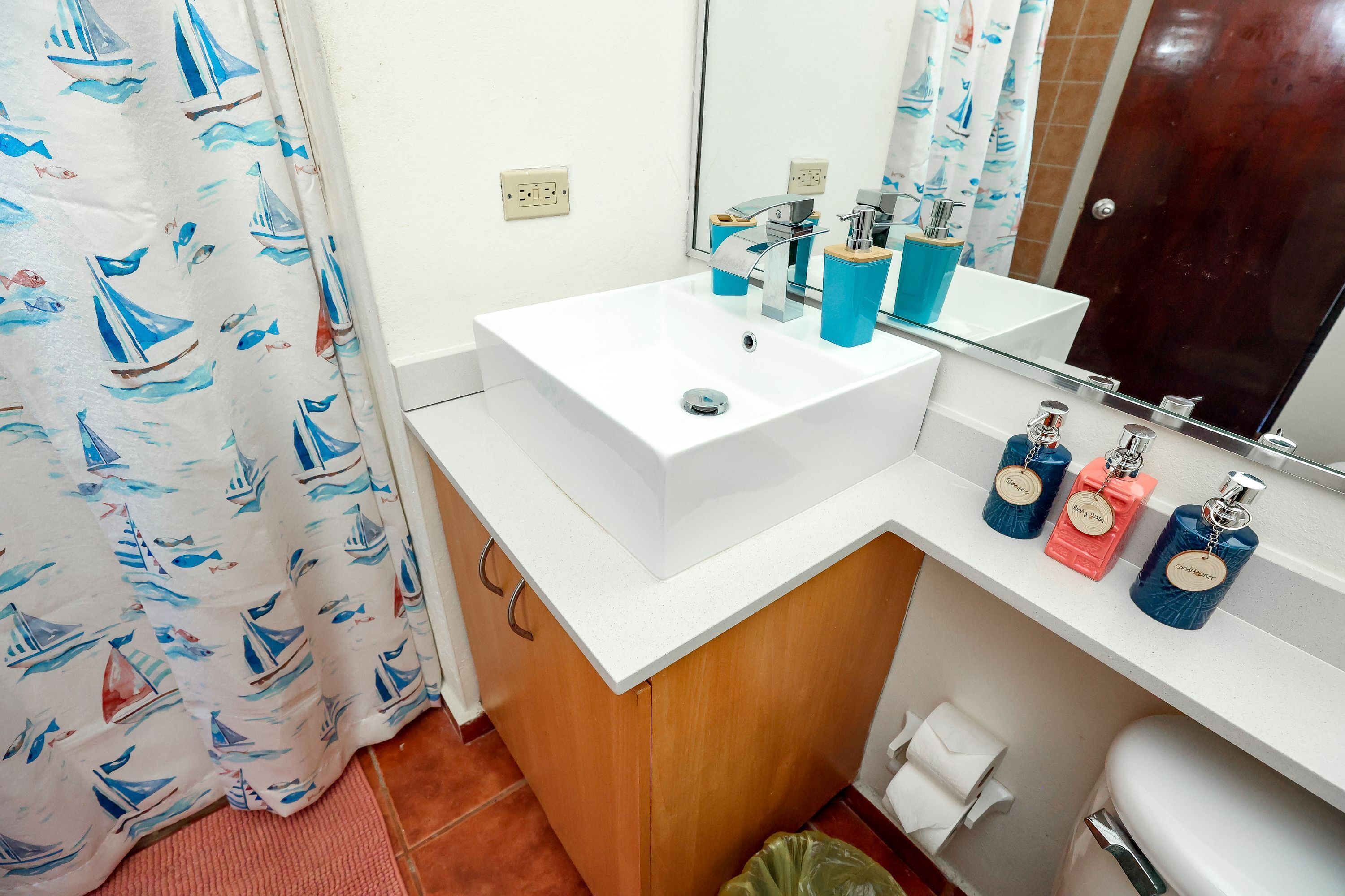 A bathroom with a white sink, blue soap dispensers, and a mirror above the sink.