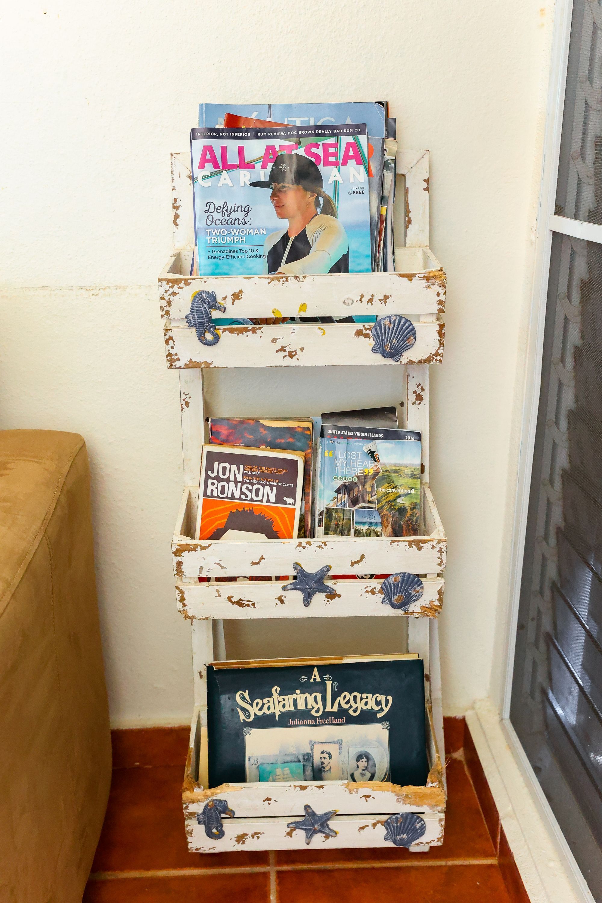A rustic bookshelf with a nautical theme, featuring books and decorative shells.