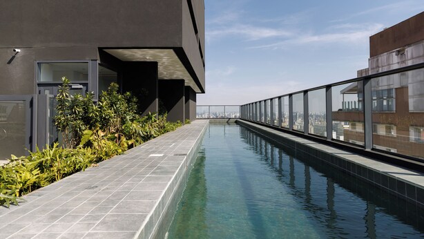 Ein Pool auf dem Dach mit Blick auf die Stadt, moderne Architektur und einer Glasbrüstung.