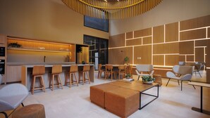 Ein modernes Interieur mit Küchenbereich, Barhocker, Esstisch und einer Sitzecke mit Sofa und Sesseln.