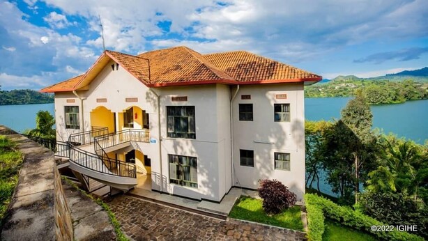 A two-story building with a red-tiled roof, a balcony, and a view of a lake. - Bethany Hotel Karongi (Bwishyura)