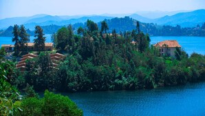 A lakeside property with multiple buildings surrounded by dense greenery and mountains in the background. - Bethany Hotel Karongi (Bwishyura)