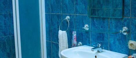 Un baño con un lavamanos blanco, azulejos azules y un perchero para toallas.