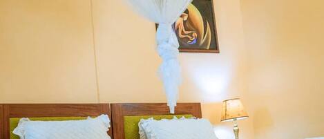 Una habitación de hotel con una cama, una mesita de noche con lámpara y un cuadro en la pared.