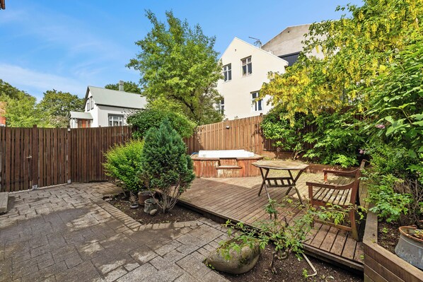 A backyard with a wooden deck, hot tub, and patio furniture. - Central studio apartment (Reykjavik)