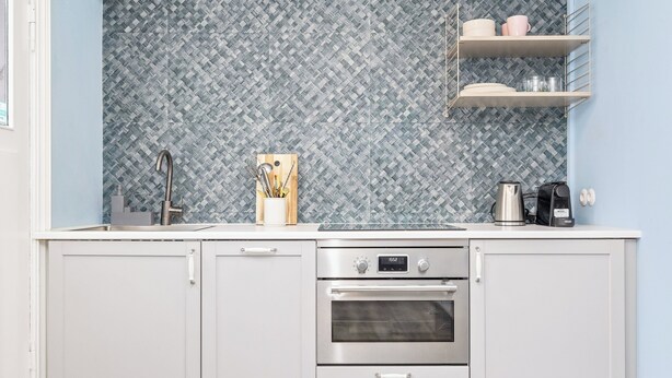 A kitchen with a patterned backsplash, stainless steel appliances, and a coffee maker. - Central studio apartment (Reykjavik)