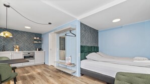 A compact bedroom with a bed, a small kitchenette, a dining area, and a walk-in closet. - Central studio apartment (Reykjavik)