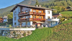 A multi-story hotel with balconies adorned with flowers, set against a mountainous backdrop. - Apartment in Pitztal With Mountain Views (Arzl im Piztal)