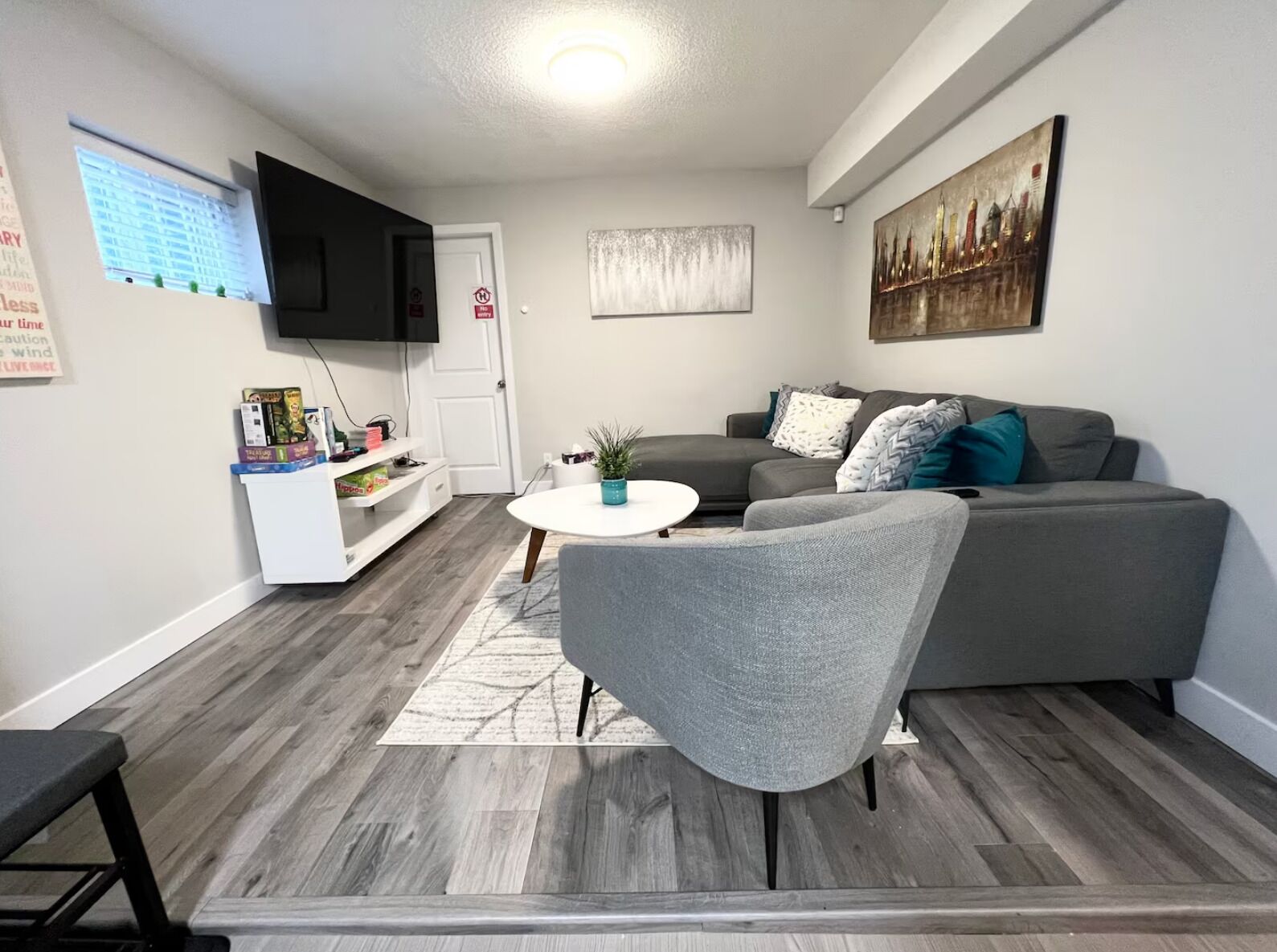 A modern living room with a grey sofa, a white coffee table, and a flat-screen TV mounted on the wall.