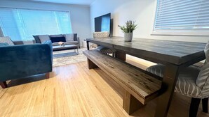 Ein modernes Wohnzimmer mit einer Holzbank, einem Sofa und einem Esstisch.