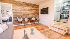 Un salon moderne avec un mur d’accent en bois, un canapé, une table basse et un coin repas avec des chaises.