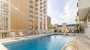A swimming pool with lounge chairs and a view of high-rise buildings. - Dazzling Waikiki Studio+KIng Bed (Honolulu)