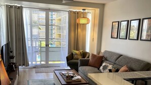 A modern living room with a sofa, coffee table, and a small kitchen area.
