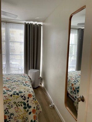 A hotel room with two beds, a large mirror, a window with curtains, and a ceiling fan.