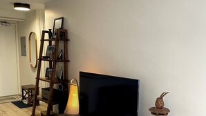 A modern living room with a flat-screen TV, wooden entertainment unit, and a decorative pineapple sculpture.