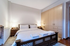 Un dormitorio con una cama grande, un armario de madera y mesitas de noche con lámparas.