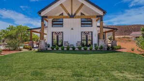 A two-story building with a covered porch, a flag, and a number '150' on the front. - Zion Riverfront Farmhouse (Virgin)