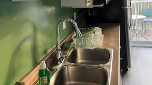 A kitchen with white cabinets, stainless steel sinks, and a green wall. - Confortable Sunny Sky  (Gatineau)