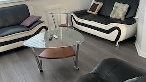 A modern living room with a glass coffee table, two sofas, and a small wooden chair. - Confortable Sunny Sky  (Gatineau)