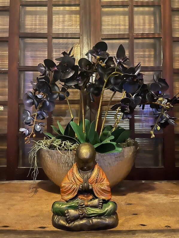 Experience tranquility with a serene Buddha statue surrounded by dark purple orchids in a peaceful indoor setting.
