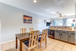 Dining area with a dark wood table and four light wood chairs featuring patterned navy cushions.