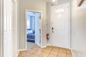 Entryway with glossy beige tile floors, a white front door featuring a semi-circular window, and an open bedroom door.