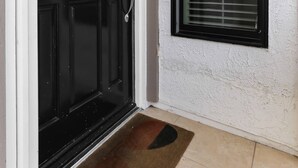 Una puerta negra con un panel de vidrio y una ventana con persianas.