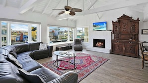 A spacious living room with a large sectional sofa, a fireplace, a television, and a view of the outside.