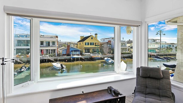 A room with a large window overlooking a harbor with boats and buildings.