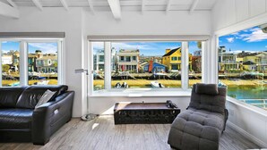 A modern living room with a large window offering a view of colorful buildings and a body of water.