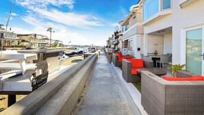 A coastal hotel with outdoor seating, a concrete pathway, and a view of the marina.