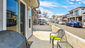 A street view with a covered outdoor seating area, a grill, and a row of parked cars. - Newport Beach Retreat Steps to Sand, Boardwalk and Pier (Newport Beach)