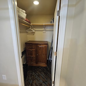 A small closet with wooden cabinetry, a hanging rack, and a patterned carpet. - Rural, high desert, private.  Hot Tub, fire pit, fully fenced, views for days! (Flagstaff)