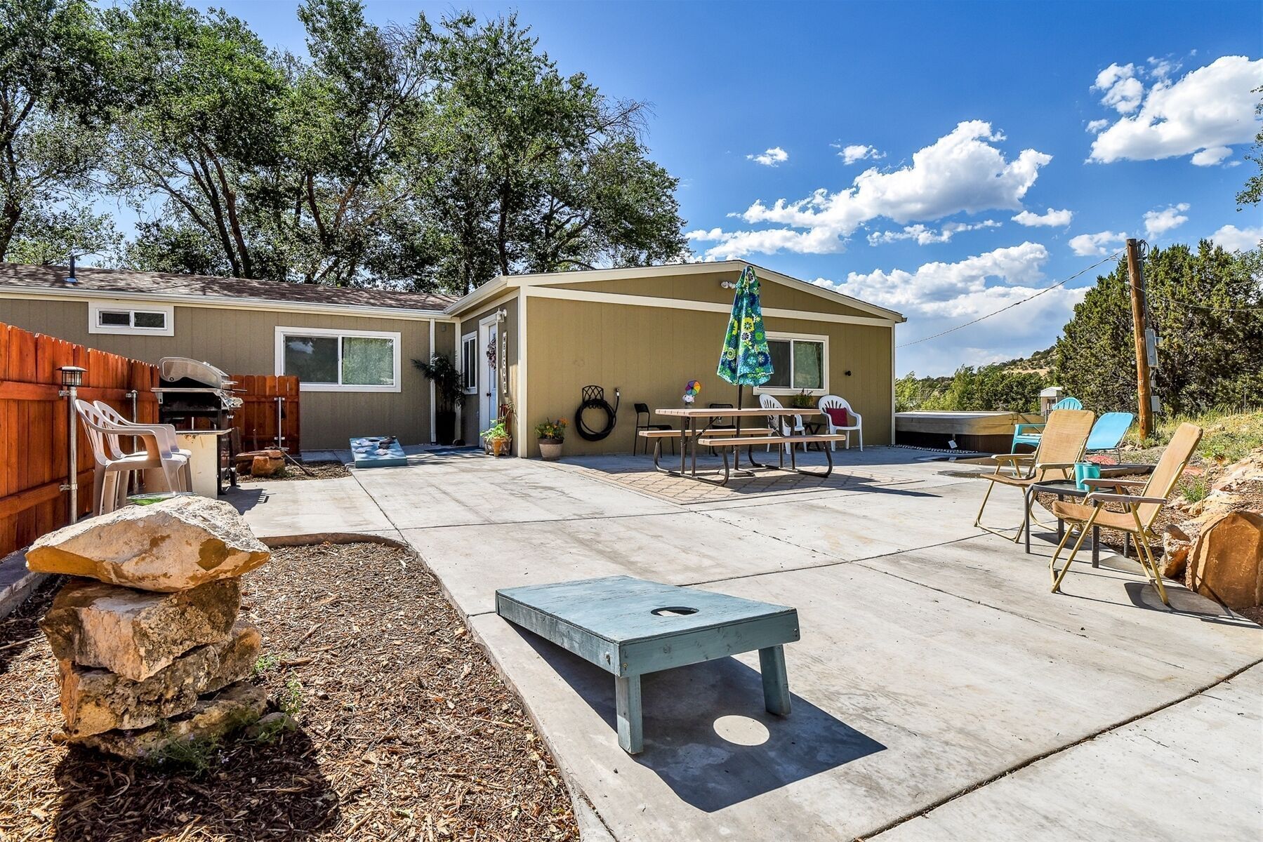 A backyard with a barbecue, patio furniture, and a stone feature.