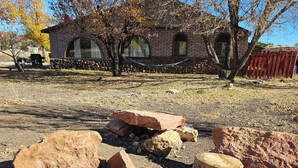 Un espacio al aire libre rústico con un hogar para fuego rodeado de rocas y un tocón de madera.