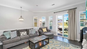 A modern living room with a grey sectional sofa, a coffee table, and a patterned rug. - Newport Retreat B – Walk to Sand (Newport Beach)