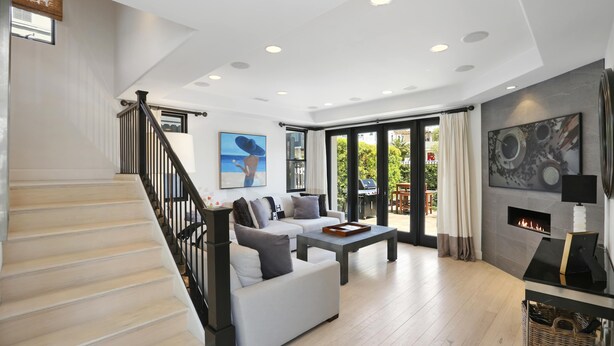 Un vaste espace de vie comprenant un escalier, une cheminée et une grande fenêtre donnant sur un jardin.