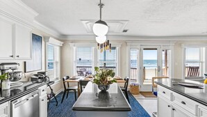 Una cocina amplia con una isla central, armarios blancos y vistas a la playa.