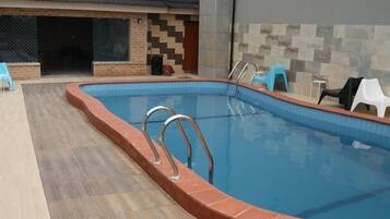Una piscina interior con un borde de baldosas, una pared de ladrillo y una pared de baldosas con un diseño geométrico.