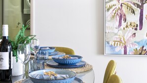 A dining table set with blue plates, a wine bottle, and glasses. - 2 Bedroom 2 Bathroom Ocean View Unit at Chevron (CHEV 3204 - 3N - NB) (Surfers Paradise)