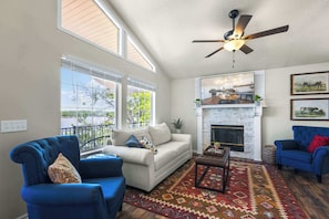 A living room with a sofa, armchairs, a fireplace, and a ceiling fan.